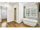 Bright bathroom featuring a freestanding tub, glass shower, plantation shutters and wooden floors at 710 Cox Rd, Roswell, GA 30075