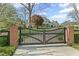 Elegant home entrance with brick columns and black wooden gate leading to a lush property at 710 Cox Rd, Roswell, GA 30075