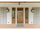 Charming front entry with a wooden door, sidelights, lanterns, and grey shutters at 710 Cox Rd, Roswell, GA 30075