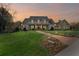 Expansive two-story home at sunset features a brick path with lush landscaping and a manicured lawn at 710 Cox Rd, Roswell, GA 30075