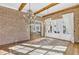 Living room featuring brick walls, exposed beams, decorative chandeliers, and a view of living area at 710 Cox Rd, Roswell, GA 30075