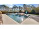 Sparkling swimming pool featuring a central spa and lounge chairs, surrounded by lush landscaping and clear blue skies at 710 Cox Rd, Roswell, GA 30075