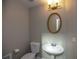 Small bathroom with pedestal sink, oval mirror, and white toilet at 1444 Tether Ln, Mcdonough, GA 30253