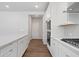 White kitchen with stainless steel appliances and hardwood floors at 6949 Melody Dr, Buford, GA 30518