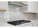 Modern kitchen with white cabinets, gas cooktop and stainless steel range hood at 6949 Melody Dr, Buford, GA 30518