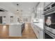 Spacious kitchen features stainless appliances, white cabinets, an island with stone countertops and hardwood floors at 125 Drummond Pl, Covington, GA 30014