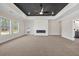 Large living room with a modern fireplace, dark tray ceiling, and backyard views from multiple windows at 125 Drummond Pl, Covington, GA 30014
