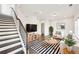 Bright living room with modern decor, including a striped rug, plants, and an adjacent staircase at 434 Herring Dr, Acworth, GA 30102