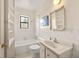 Bright bathroom with white tiled walls, vanity, and a window above the bathtub at 318 Stewart Nw Ave, Marietta, GA 30064