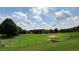 Expansive fenced dog park with green grass, shade trees, and picnic shelters under a sunny, cloudy sky at 318 Stewart Nw Ave, Marietta, GA 30064