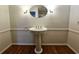 Classic pedestal sink with a round mirror and sconce lighting on gleaming hardwood floors at 1409 Oakridge Cir, Decatur, GA 30033