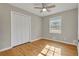 Sunlit bedroom featuring hardwood floors, large window, ceiling fan, and a closet, offering comfort and style at 5380 Saint Lo Ln, Atlanta, GA 30349