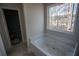 Bright bathroom features a soaking tub beneath a large window offering views of the wooded property at 101 Azalea Dr, Villa Rica, GA 30180