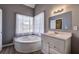 Bright bathroom features a corner soaking tub next to a window, and white vanity at 3634 Autumn Ridge Pkwy, Marietta, GA 30066