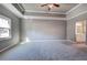 Expansive main bedroom with tray ceiling, gray walls, carpet, and doorway to an ensuite bathroom at 3634 Autumn Ridge Pkwy, Marietta, GA 30066