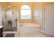 Bright bathroom features a large tub under an arch window and a glass enclosed shower at 907 Hannah Ct, Loganville, GA 30052