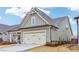 Side angle of home's exterior features a double garage door, landscaped lawn, and neutral paint at 595 Everton Pl, Grayson, GA 30017