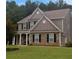 Two story home with a charming porch and stone veneer, and well manicured lawn at 324 Mary Dr, Mcdonough, GA 30252