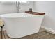 Elegant freestanding bathtub with a wooden bath caddy and modern faucet fixtures at 1586 Sungrown Way, Mcdonough, GA 30253