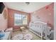 A charming Bedroom with a white crib, pink walls, and decorative flower accents at 1450 Riverrock Trl, Riverdale, GA 30296