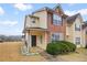 Townhouse with a covered porch, brick and vinyl siding, complemented by lush green bushes at 1450 Riverrock Trl, Riverdale, GA 30296