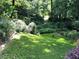 The backyard features a well-manicured lawn, a small gate, lush greenery, and mature trees at 3479 Chestnut Dr, Atlanta, GA 30340