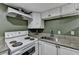 This kitchen features white cabinetry, granite countertops, and a white oven range with a vent hood above at 3479 Chestnut Dr, Atlanta, GA 30340