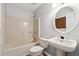 Bathroom with beige tub, white sink, and a round mirror at 3562 Ontario Ct, Buford, GA 30519