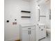 Bright laundry room featuring white cabinetry, floating shelves, and connection to the bathroom at 474 Fairlock Nw Ln, Atlanta, GA 30331