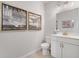 Small bathroom showing a toilet, sink, vanity, and modern artwork above the toilet at 443 Village Ln, Fairburn, GA 30213