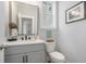 Bathroom featuring gray vanity, toilet, decorative mirror, and stylish wall art at 646 Brashy St, Woodstock, GA 30188