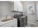 Convenient laundry room with modern washer and dryer units, a utility sink, and patterned flooring at 646 Brashy St, Woodstock, GA 30188