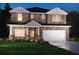 Two-story stone home featuring a two-car garage, covered porch, and manicured lawn at 6900 Winchester Pl, Fairburn, GA 30213