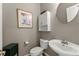 Powder room featuring pedestal sink, commode, and decorative accents at 2352 Kelman Pl, Dacula, GA 30019