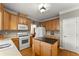 Well-lit kitchen with wood cabinets, white appliances, and a functional center island provides ample cooking space at 2352 Kelman Pl, Dacula, GA 30019