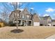 Lovely two-story home with a blend of siding and brick, framed by a mature tree and lush greenery under a bright sky at 6120 Sparrow Ln, Cumming, GA 30028