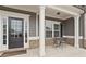 Close-up of a welcoming front porch with elegant columns, a stylish door with sidelights, and a charming outdoor seating arrangement at 6120 Sparrow Ln, Cumming, GA 30028