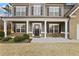 Inviting front porch featuring classic white columns, a cozy seating area, and a beautifully designed front door at 6120 Sparrow Ln, Cumming, GA 30028