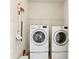 Modern laundry room with front-load washer and dryer with shelving for storage at 6120 Sparrow Ln, Cumming, GA 30028