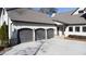 Three-car garage with dark gray doors and stone accents at 5152 Boulder Bluff Way, Suwanee, GA 30024