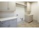 Laundry room with gray cabinets, quartz countertops, and tile floor at 5152 Boulder Bluff Way, Suwanee, GA 30024