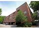 Brick condo building with covered parking, multiple balconies, and surrounded by mature shade trees at 351 Washington Ne Ave # 208, Marietta, GA 30060