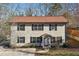 Two-story home featuring neutral siding, black shutters, a brown roof, and mature trees and landscaping at 3683 Rolling Pl, Conley, GA 30288