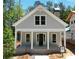 Charming exterior showcasing a covered front porch with columns, a gray facade, and a brick chimney, nestled amongst lush trees at 11792 Serenbe Ln, Chattahoochee Hills, GA 30268