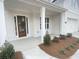 View of the covered front porch with a decorative wood door and manicured garden at 3345 Hillshire Dr, Cumming, GA 30028