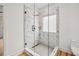 Glass enclosed shower with white marble walls, window and modern fixtures in neutral bathroom at 2208 Baker Nw Rd, Atlanta, GA 30318