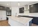 Modern kitchen featuring a large island, stainless steel appliances, dark cabinetry and herringbone backsplash at 688 Calvet Way, Cumming, GA 30041