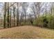 Wooded backyard with a spacious lawn and leaf-covered ground at 4598 Flint Hill Rd, Austell, GA 30106