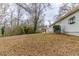 Large backyard with mature trees and a sloped lawn covered in leaves at 4598 Flint Hill Rd, Austell, GA 30106