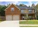 Charming two-story home features a brick facade, two-car garage, and a well-manicured lawn at 7940 White Oak Loop, Lithonia, GA 30038